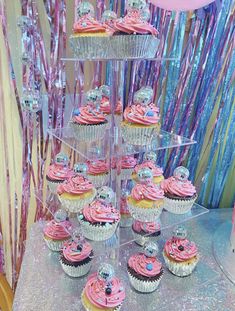 cupcakes are arranged on a cake stand in front of streamers