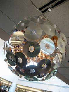 a circular light fixture with cds hanging from it's sides in an office building