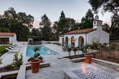 an outdoor fire pit in the middle of a backyard with a pool and patio furniture