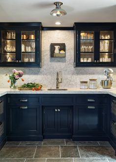 a kitchen with black cabinets and marble counter tops