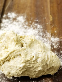 a ball of dough sitting on top of a wooden table covered in powdered sugar