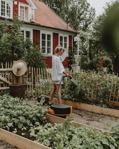 a woman watering her garden in front of a house