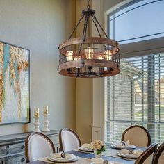 a chandelier hanging over a dining room table with place settings on the plates