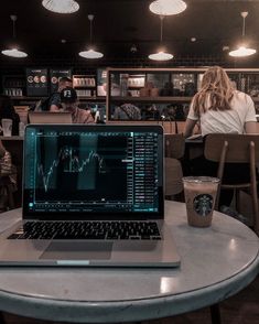 a laptop computer sitting on top of a table next to a cup of starbucks coffee