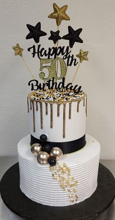 a white and black birthday cake with gold stars on top that says happy 50th birthday