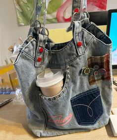 a handbag made out of old jeans with patches and buttons on the front pocket