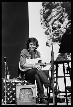 a man sitting on top of a chair next to a guitar