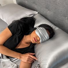 a woman laying on top of a bed with a blindfold over her face and head