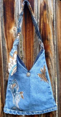 a denim purse hanging on the side of a wooden fence