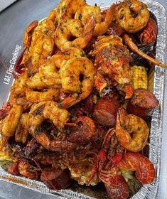 a tray filled with cooked shrimp and corn on the cob