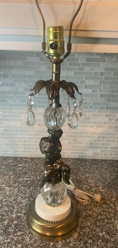 a table lamp that is sitting on top of a marble counter with a glass bead candle holder