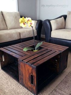 a coffee table made out of pallet wood with a flower in the center and two couches behind it