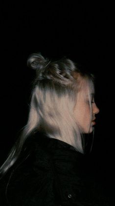 a woman with blonde hair is standing in the dark