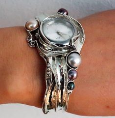 From Porans Watches collection: Unique silver cuff watch with a white, black, and cream Pearls inlaid. Dimensions:  Max front Width: 39 mm\ 1.56 inches. Back width: 10 mm\ 0.39 inches.  Our watch is top quality stainless still, analog, Japanese movement with water resistance (up to 3 atmospheres) and it is powered by a battery that lasts about 3 years. The battery can be exchanged. Please notice that because the watch is made to order the watch mechanism part may look different than the picture, Watch Mechanism, Watches Collection, Womens Cuff Bracelets, Unique Women, Wide Cuff Bracelets, Cuff Watch, Pearl Cream, Wide Cuff, Silver Cuff Bracelet