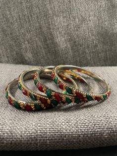 Set of 4 gold tone bracelets with green and red oval stones and gold colored rhinestones. 2.5 inner diameter. Festive Jeweled Metal Bracelets, Festive Metal Jeweled Bracelets, Green Beaded Metal Bangle Bracelets, Green Metal Bracelets For Festive Occasions, Green Jeweled Bangle Bracelets, Oval Green Jeweled Jewelry, Festive Red Jeweled Bangle, Festive Red Metal Bangle, Multicolor Rhinestone Bangle Jewelry