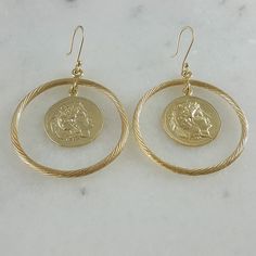 Enhance your elegance with our exclusive Artisan Gold Plated Medallion Earrings, a perfect gift for her. These meticulously crafted earrings feature an alluring design with a textured hook that adds a touch of uniqueness. Suspended within the large 45mm hoop, a genuine Alexander Coin dangles, infusing a sense of history and charm into modern fashion.Our dainty coin earrings are designed to be the epitome of sophistication and grace. Measuring 65mm in length and 45mm in width, these timeless piec Ceremonial Engraved Coin-shaped Jewelry, Vintage Handmade Coin Earrings, Vintage Silver Coin Earrings, Roman Coin Earrings, Medallion Earrings, Antique Coin-shaped Metal Jewelry, Crafted Earrings, Ancient Coin, Coin Earrings