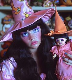 a close up of a doll wearing a witches hat and holding a doll in her hand