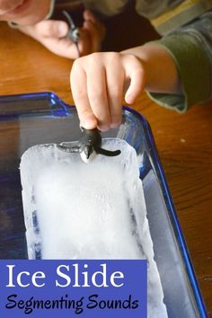 a young boy is making an ice slide with tongs and water in a plastic container