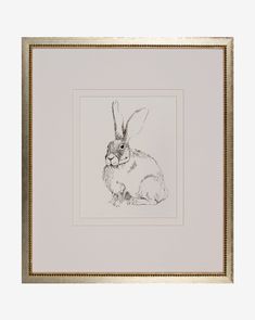 a black and white drawing of a rabbit in a gold frame on a white wall