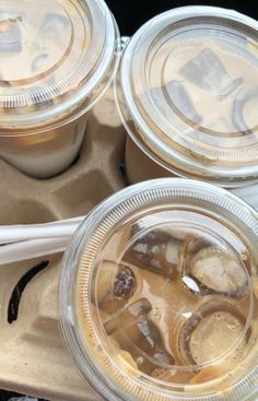 three plastic cups filled with ice cream and some type of drink on top of a tray