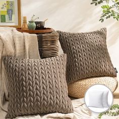 two gray knitted pillows sitting on top of a bed next to a potted plant