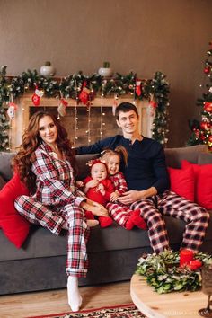 a man and woman are sitting on a couch with their two children in matching pajamas