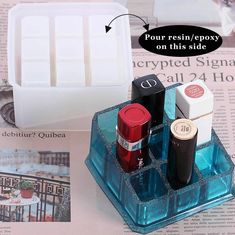 an assortment of lipstick and nail polishes in a plastic container on top of newspaper pages