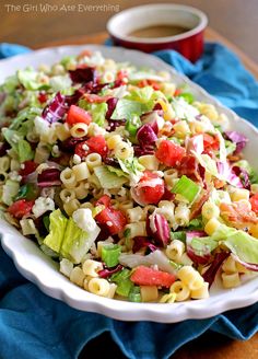 a white bowl filled with pasta salad next to a cup of coffee on a table