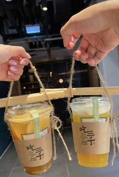 two people holding up cups with drinks in them and tied to the side by twine