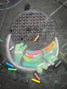 a manhole cover with chalk and crayons on the ground