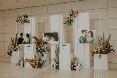 an arrangement of flowers and pictures on display in a room with white walls, flooring and tiled floors