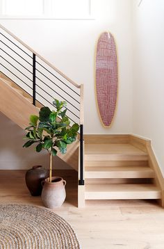 a potted plant sitting next to a stair case in front of a wooden banister