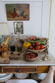 a table topped with plates and bowls filled with food next to a painting on the wall