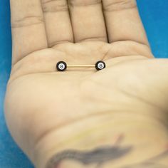 a person's hand holding two tiny black nose pins