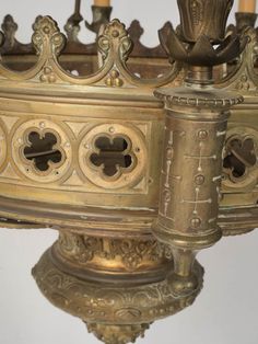 an ornate brass chandelier with candles in the center and decorative carvings on the sides