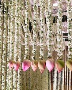 flowers are hanging from the ceiling in front of some white and pink decorations at a wedding