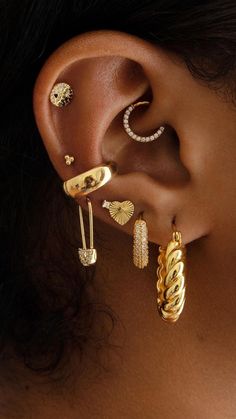 a close up of a person wearing gold ear rings and earrings with diamond details on them