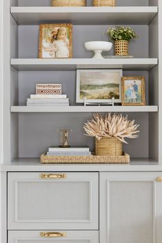 an open bookcase with pictures and other items on it, along with wicker baskets