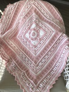 a pink crocheted blanket sitting on top of a table