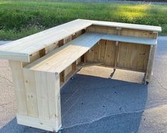 a wooden bench sitting on top of a cement ground next to a grass covered field