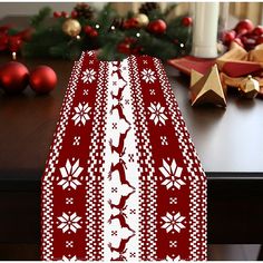 a red and white table cloth with snowflakes on it next to christmas decorations