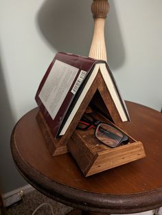 an open book sitting on top of a wooden table next to a pair of glasses