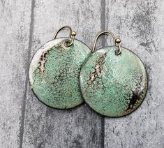 pair of green and brown earrings sitting on top of a wooden table