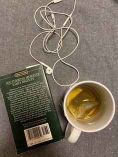 a cup of tea next to a book and headphones