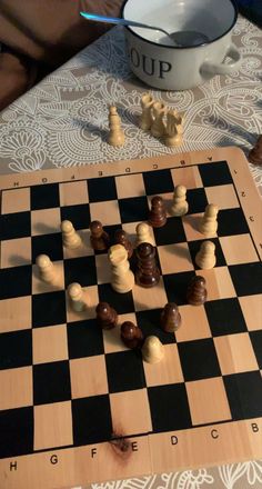 a wooden chess board with pieces on it and a white bowl sitting next to it