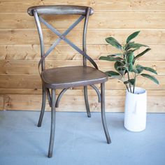 a wooden chair next to a potted plant