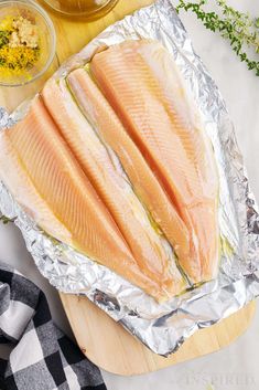 raw fish fillets on tin foil with seasoning and salt in bowls next to them