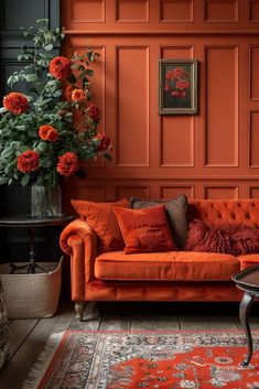 a living room with an orange couch, rug and flowers in vase on the floor