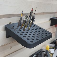 there are many screws in the holder on the wall next to some other tools