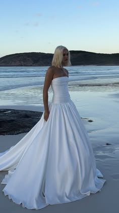 a woman in a wedding dress standing on the beach